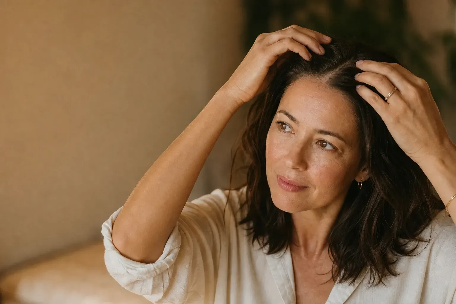 Woman lifting her hair at the part line to check scalp density and thinning at a Lake Havasu City medspa consultation