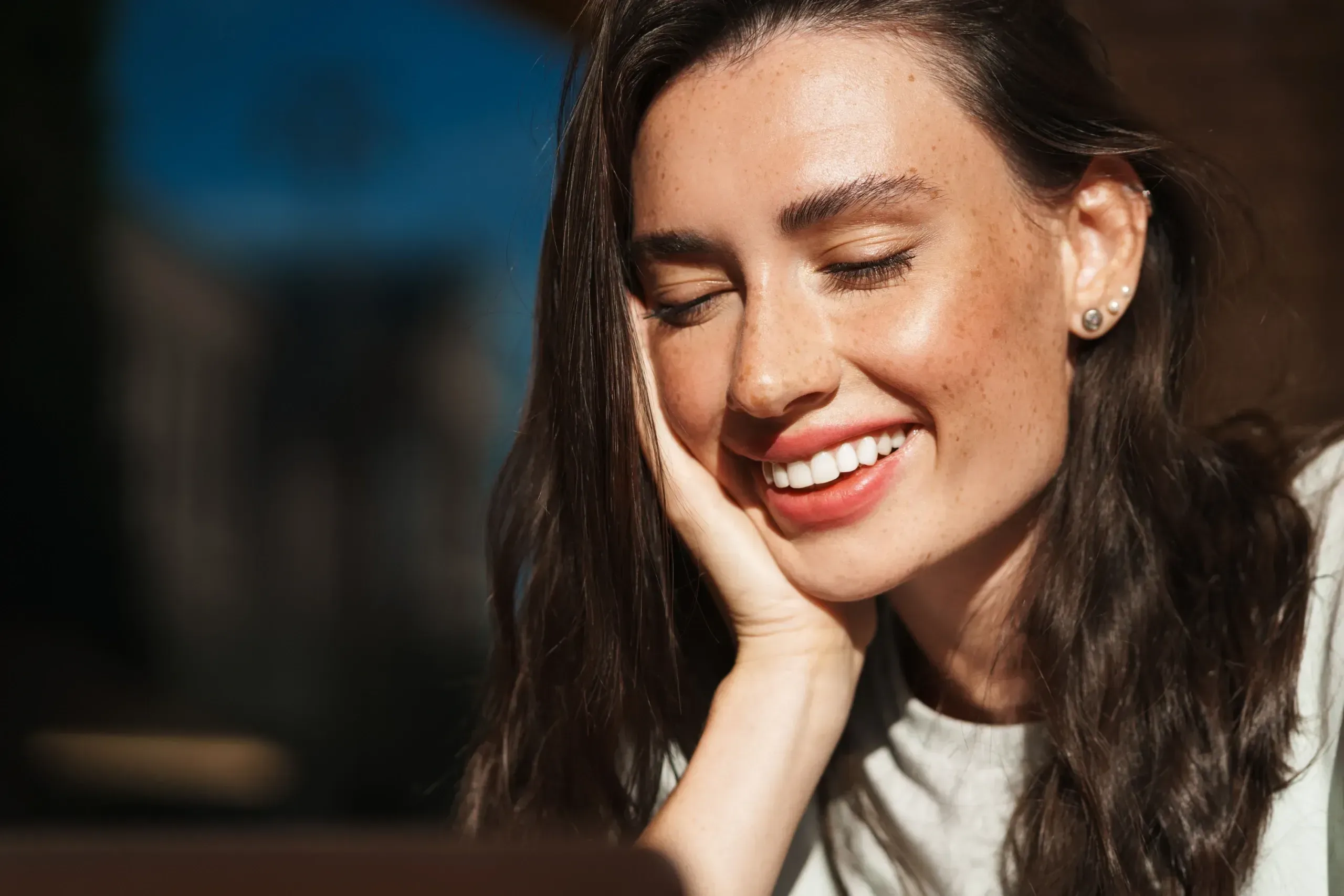 Woman studying flat brown sun spots across her cheekbones in bright desert light in Lake Havasu City